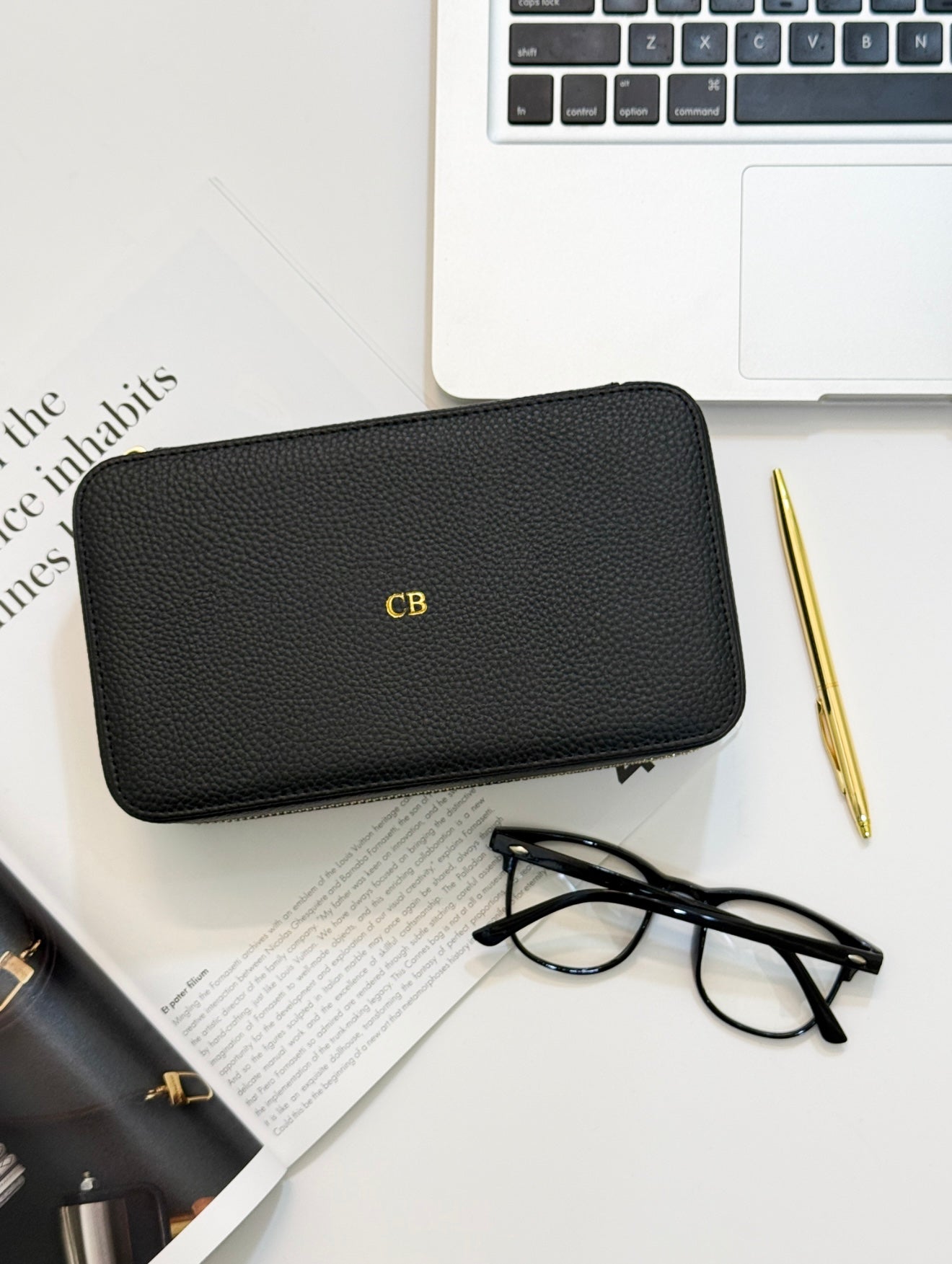 monogrammed black  jewelry case with monogram next to a gold pen, reading glasses, and a laptop 