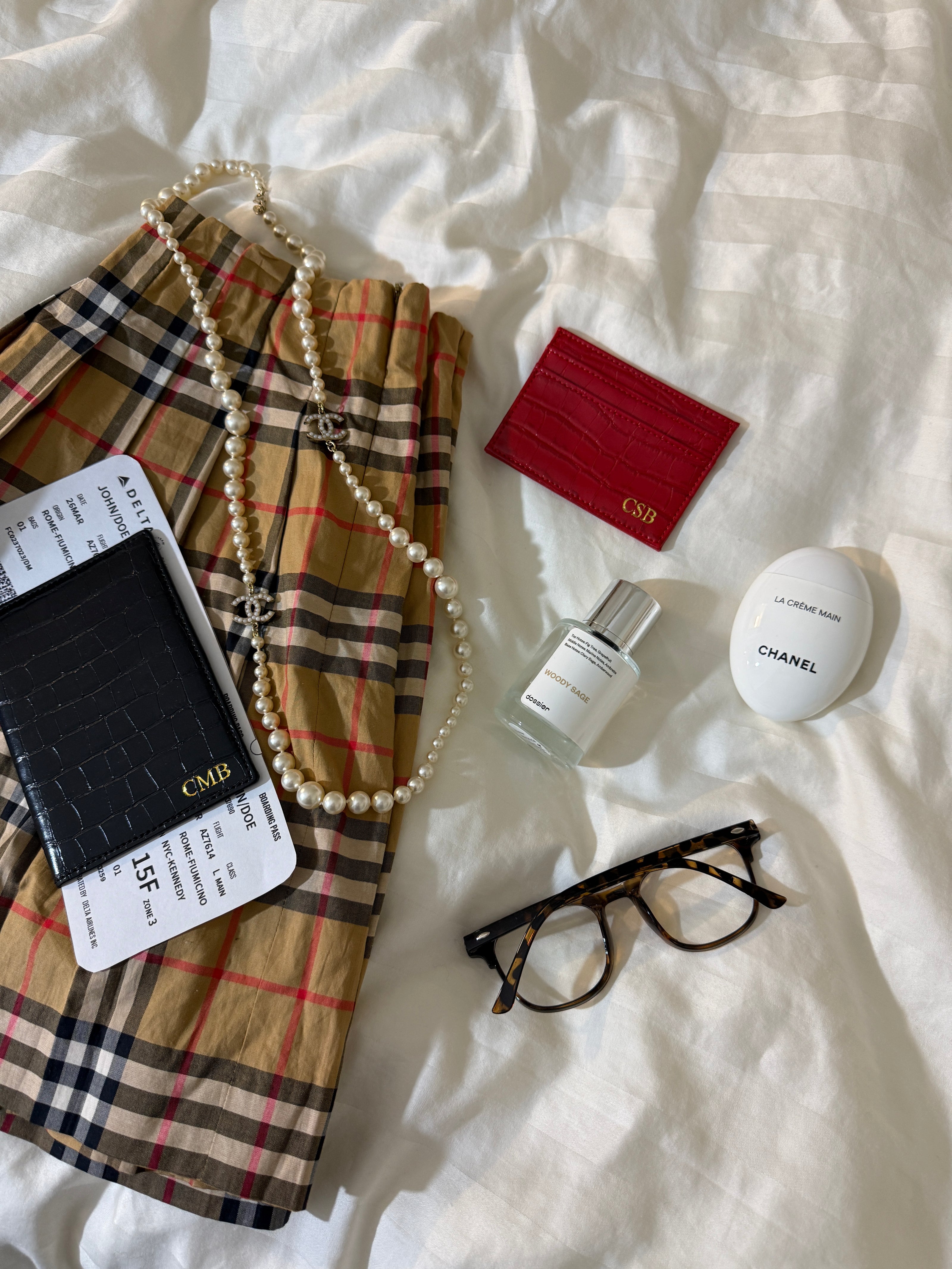 skirt with red monogrammed croc card holder, black monogrammed croc passport case, perfume, and glasses