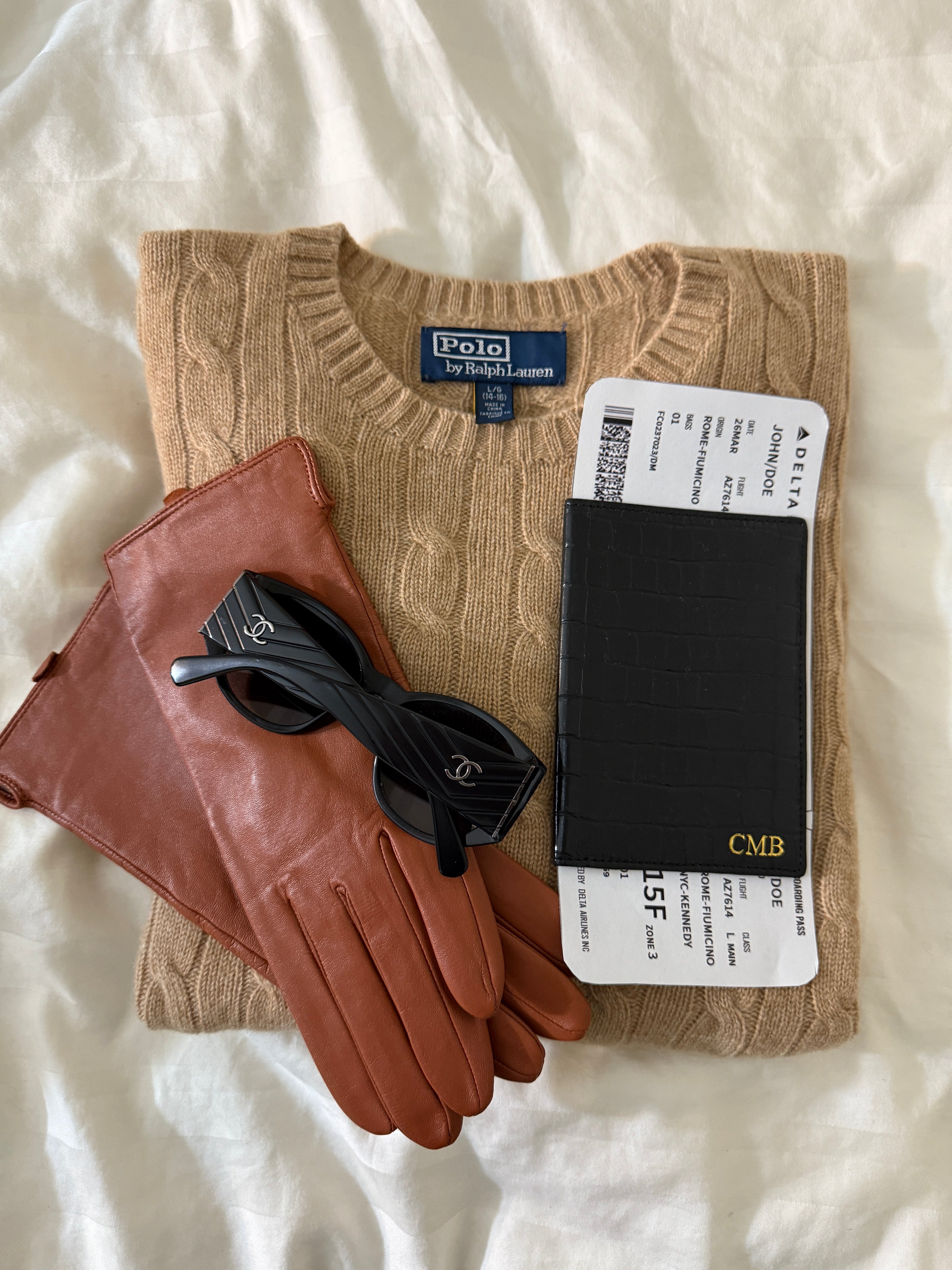 sweater with gloves, monogrammed croc passport cover, and sunglasses