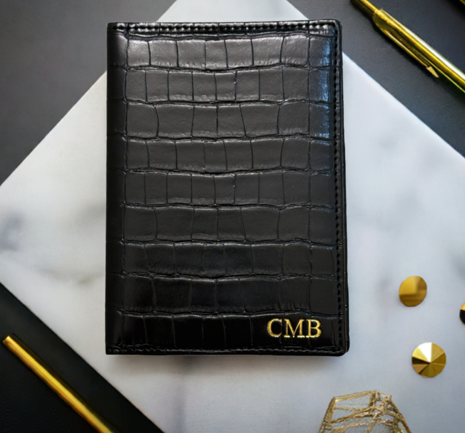 black croc monogrammed passport cover on marble background with gold pen