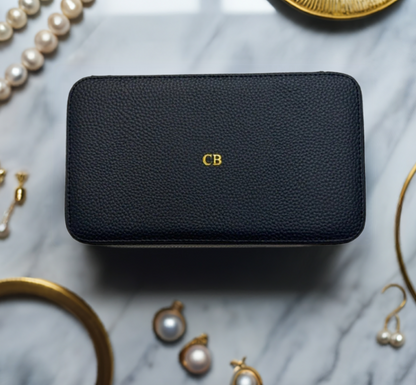 black monogrammed jewelry case surrounded by gold jewelry 